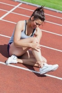 Female runner with ankle injury on track